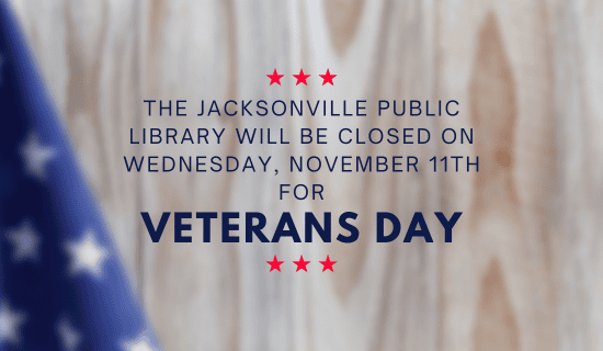 Image: a blurry image of a light wood grain background with a small portion of the American flag in the lower left corner. Text reads: The Jacksonville Public Library will be closed on Wednesday, November 11th for Veterans Day.